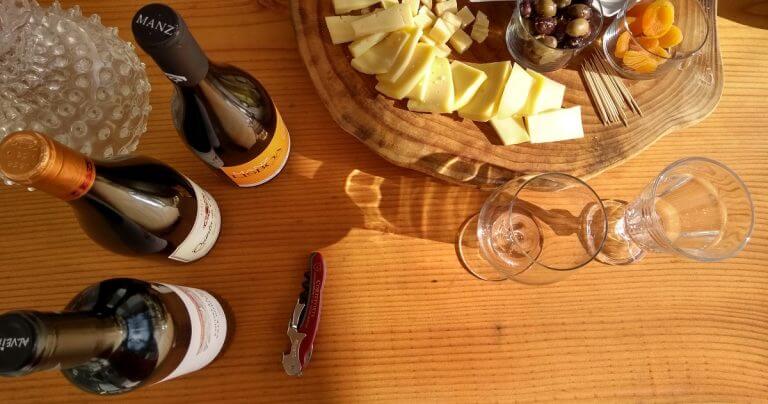 table with three bottles of wines and a plate with cheese